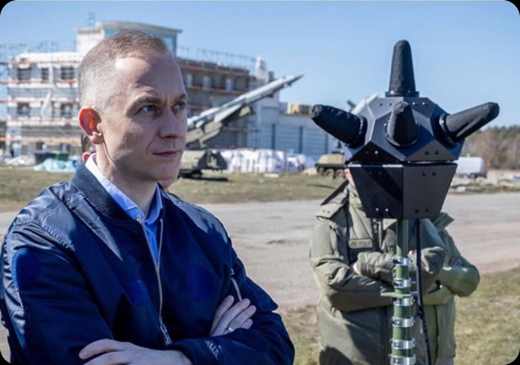 Krystian Guzowski z detektorem na tle wyrzutni na poligonie